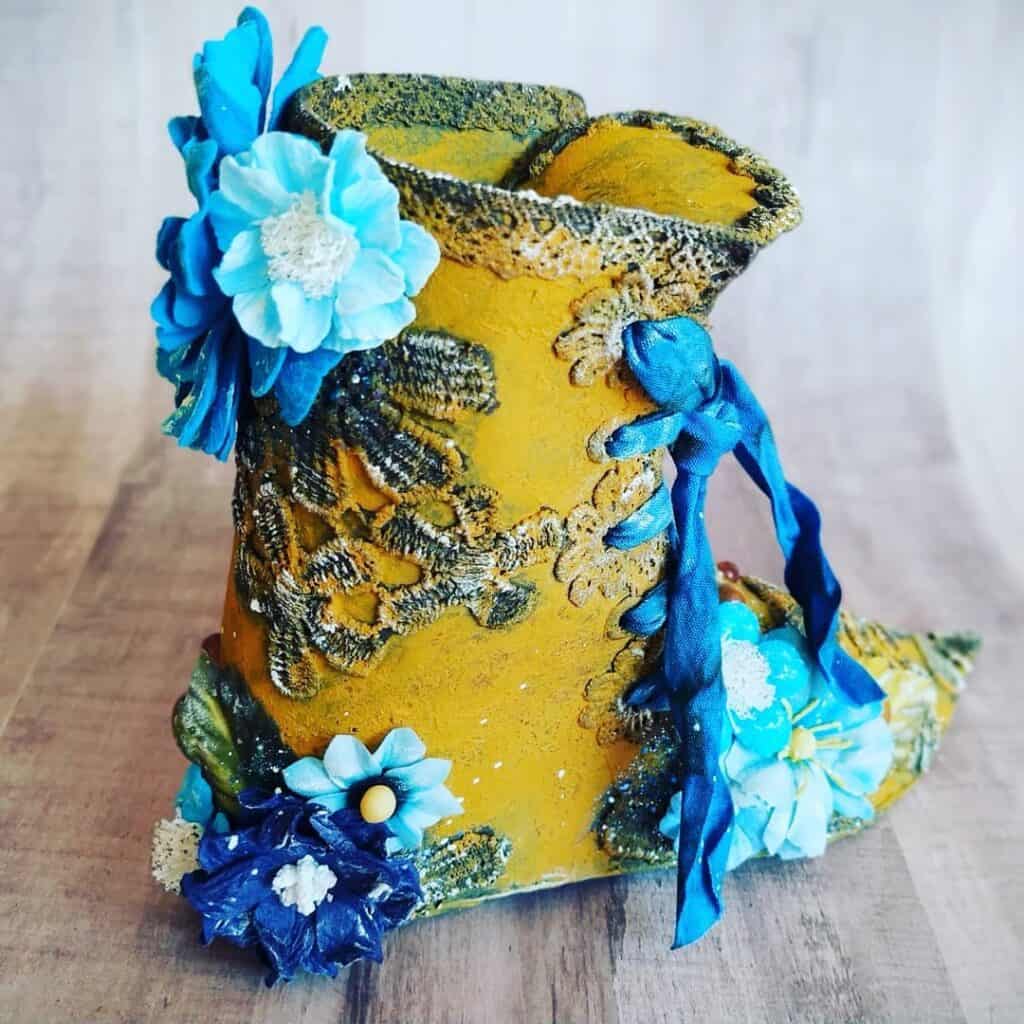 Florero decorativo artesanal con flores de terciopelo y lazos azules para decoración creativa.