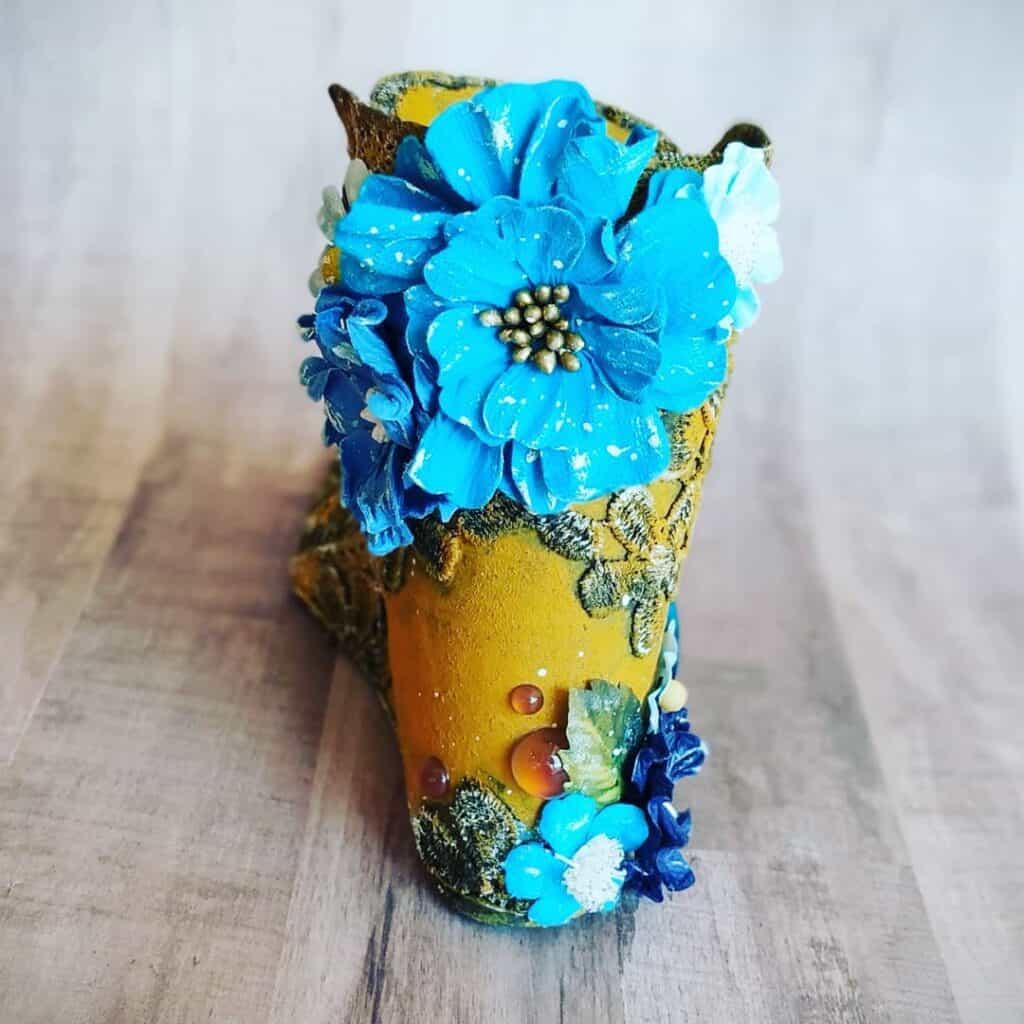 Florero decorativo con flores azules y detalles artesanales de diseño único.