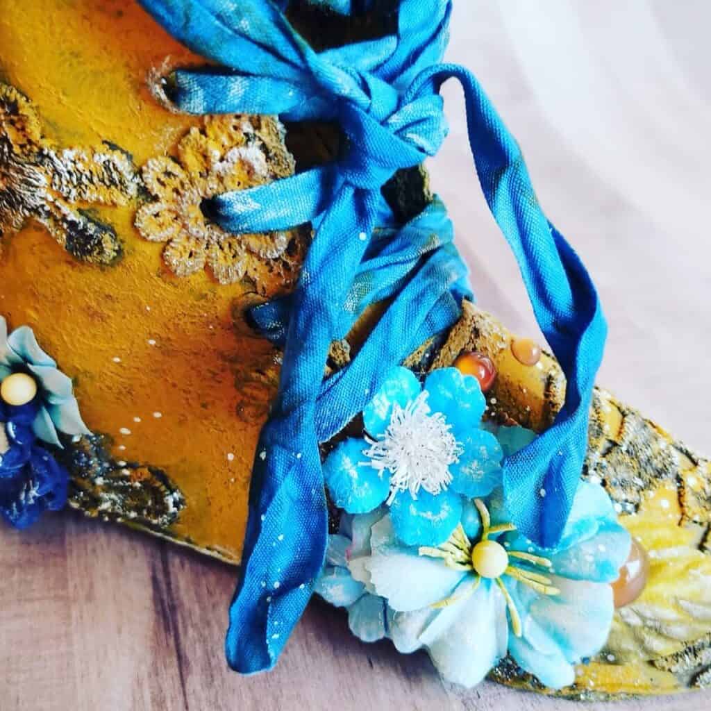 Zapato decorado artesanal con flores y cintas en tonos azules, arte en calzado.